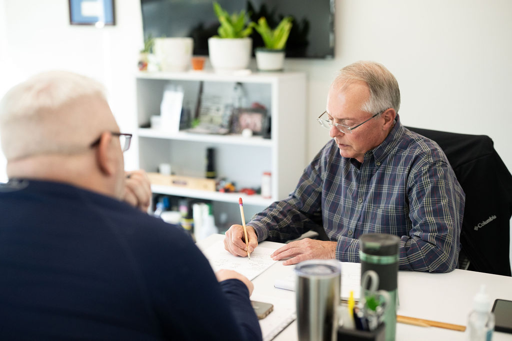 Two BerkleyNet employees sitting at a desk while reviewing workers compensation documents in an office. 