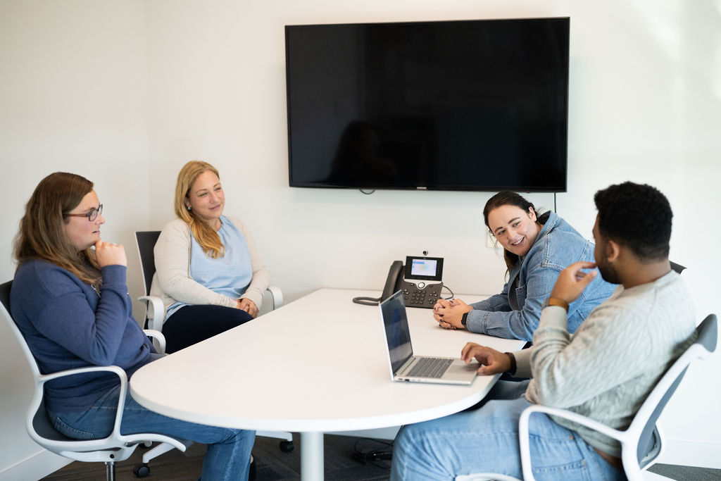 Four BerkleyNet employees attentively participating in a meeting for BerkleyNet, workers compensation insurance. 