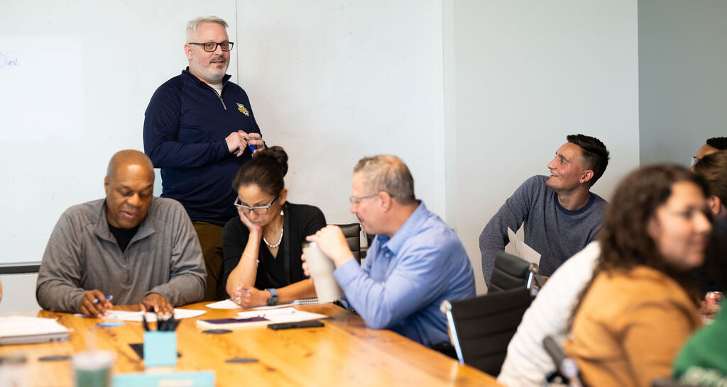 Three BerkleyNet employees attentively participating in a meeting, in a collaborative environment at BerkleyNet workers compensation insurance. 