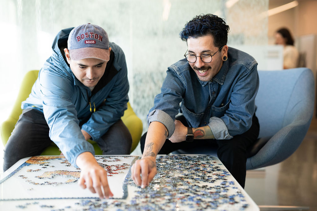 Two BerkleyNet employees in the office doing a puzzle, a positive workplace culture and team spirit for careers in workers compensation insurance industry. 